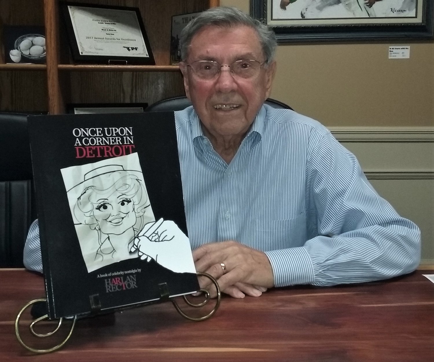 Harlan Rector shows off his book of celebrity caricatures.